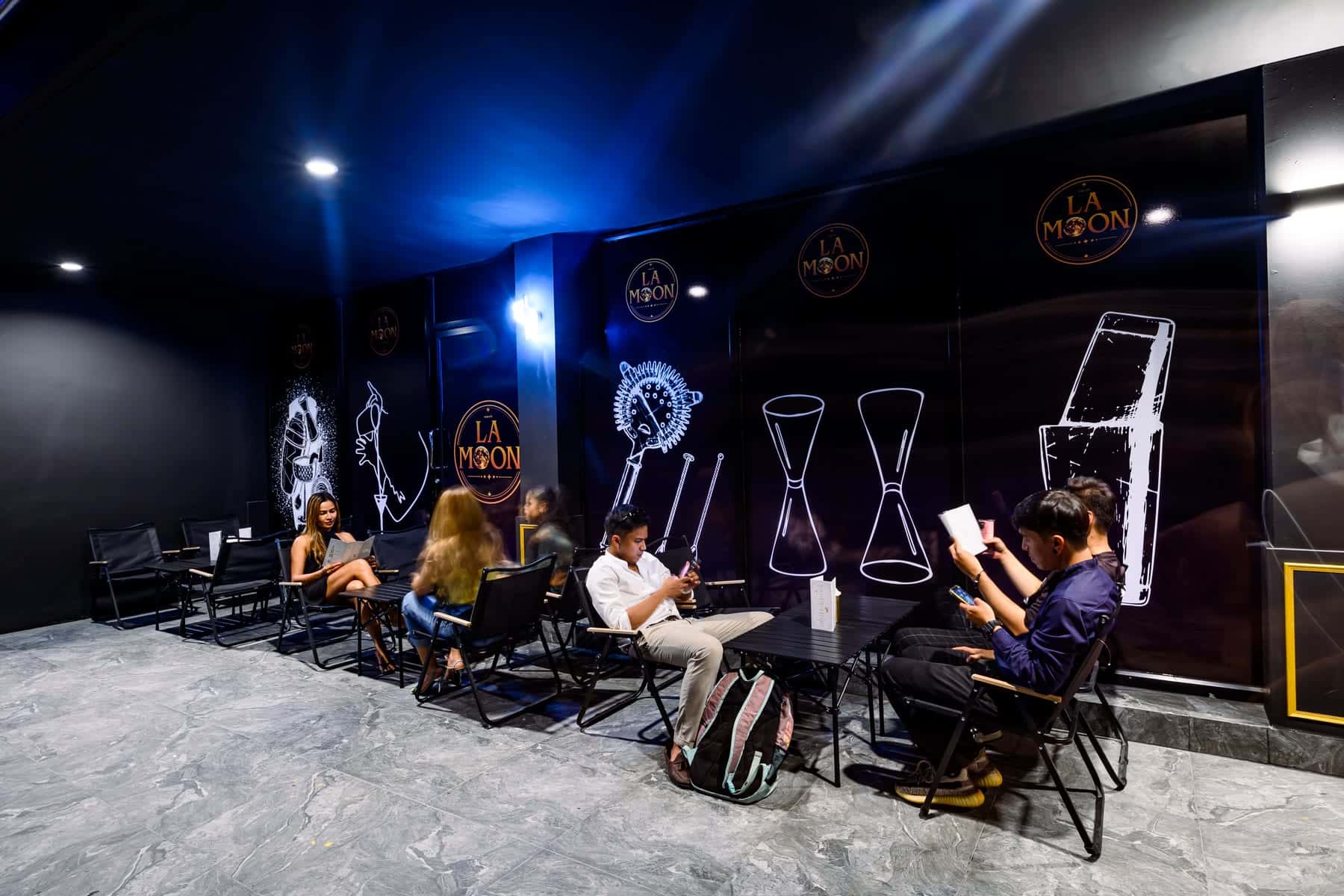 The outdoor terrace at La Moon, with neon glassware outlines along a black wall